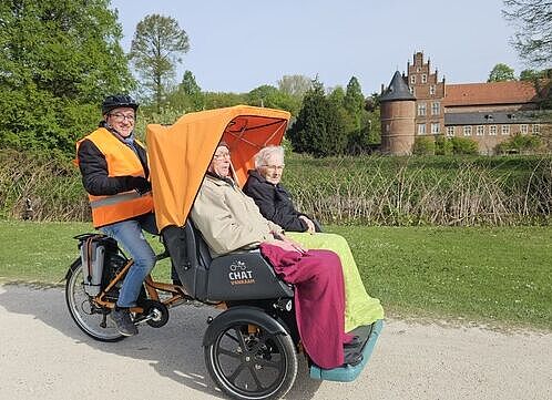 Zwei Personen werden in einer Rikscha transportiert.
