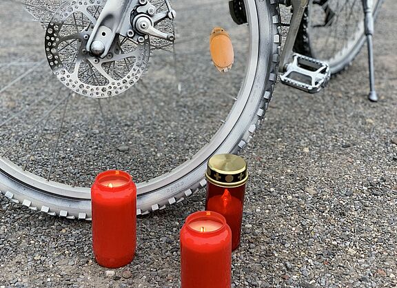 Ein weißes Ghostbike und brennende Kerzen. 